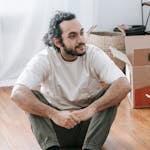 Man Sitting On Floor Beside Boxes